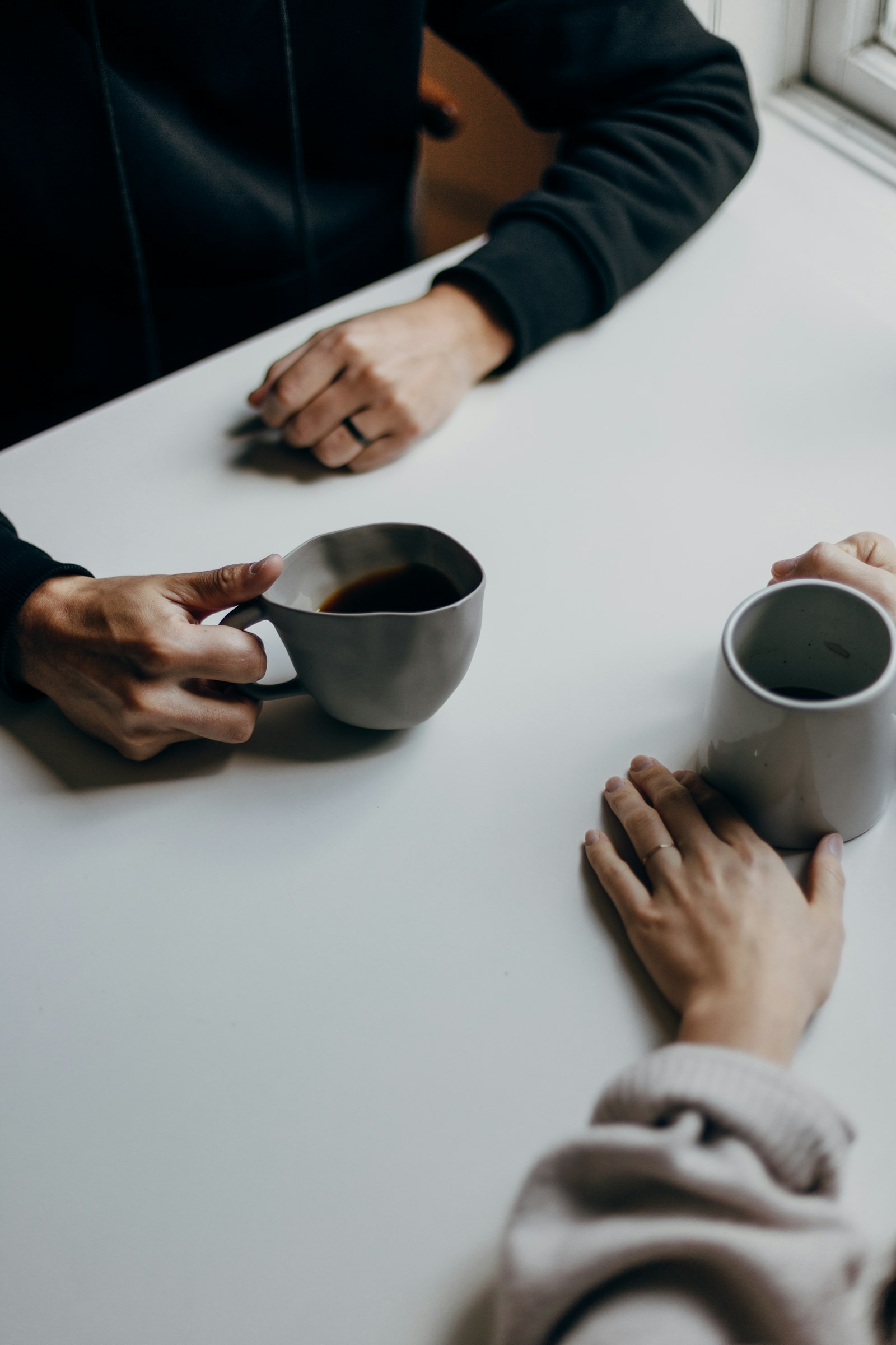 Two people talking across a table over coffee