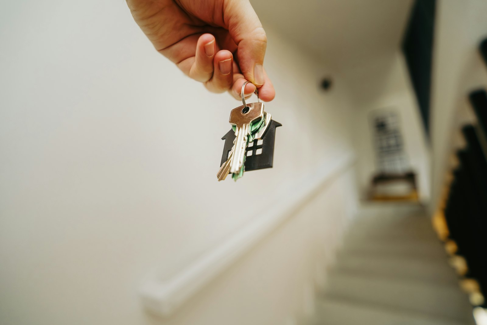 A hand holding house keys on a house-shaped keychain